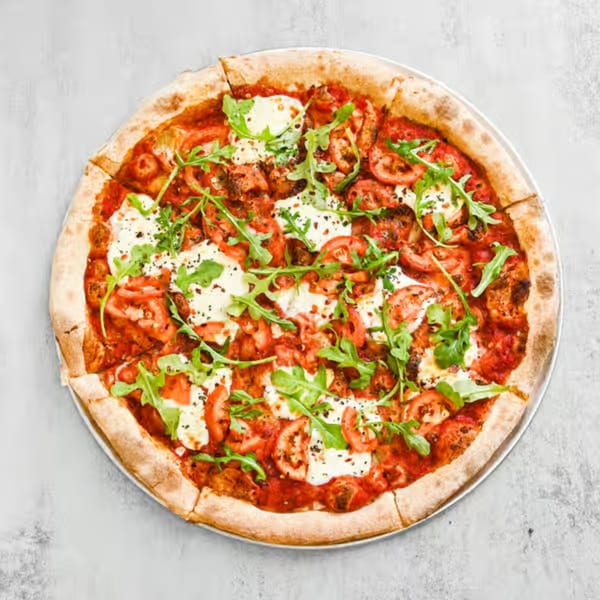 Krave Pizza and Wings' pizza with tomato sauce, fresh mozzarella, sliced tomatoes, and arugula.